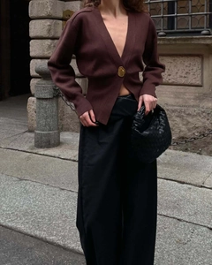 Dettaglio del cardigan in maglia marrone scuro con scollo a V e chiusura a bottone singolo