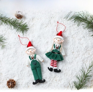 Detailed view of Christmas elf plush ornaments in green outfits on decorative snow and pine