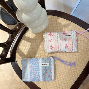 Floral fabric pouches with zippers displayed on a woven chair in a warm setting