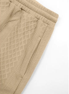 Detail of khaki waffle knit pants showing elastic waistband, side pockets and fabric texture