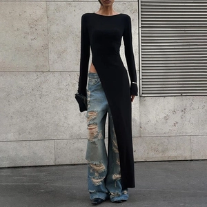 Detail eines hohen Seitenschlitzes am langärmligen Kleid über zerrissenen Jeans