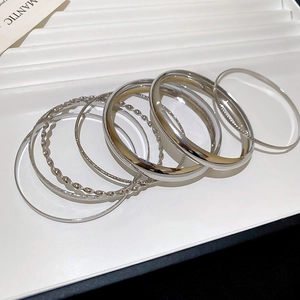 Détail d'un ensemble de bracelets argentés aux motifs torsadés et texturés sur un plateau blanc