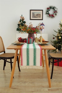 Close-up of Christmas table runner featuring woven trees and festive tassel fringe