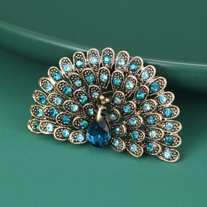 Close-up of golden peacock brooch with sparkling blue rhinestones and teardrop gem
