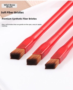 Macro shot of three makeup brushes with angled brown bristles and red glossy handles