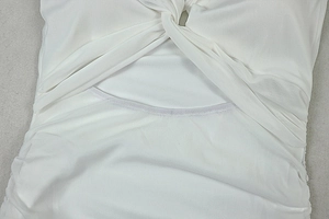 Detail of the white hollow-out dress showing cross-knotted design and pleated texture
