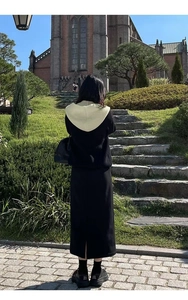 Detail view of stylish knitted top with beige hood and black maxi skirt for winter