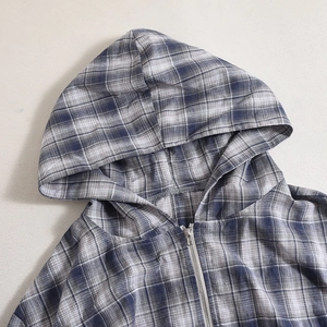 Detailopname van de blauw-wit geruite hoodie met metalen rits en hoogwaardige stofstructuur