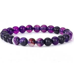 Macro shot of purple agate and black volcanic stone elastic bracelet with red accents
