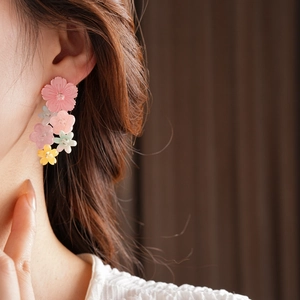 Close-up of colorful resin flower tassel earrings worn by a model in a warm setting