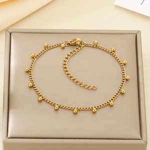 Detailed macro view of a gold bead chain bracelet on a champagne jewelry display pad