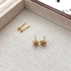 Close-up of golden flower stud earrings with zircons and gold ball earrings set