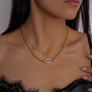 Detail of layered gold necklace with blue evil eye pendant and crystal accents on model