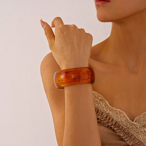 Close-up of a wide vintage amber resin bangle featuring artistic swirl patterns
