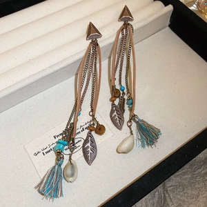 Detail of bohemian tassel earrings with bronze metal, beads and feathers in a box