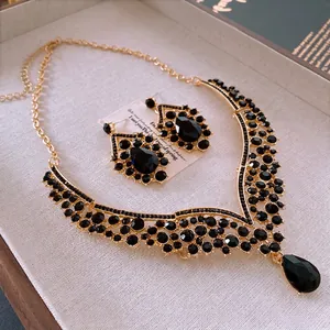 Parure collier et boucles d'oreilles dorée avec pierres noires sur plateau