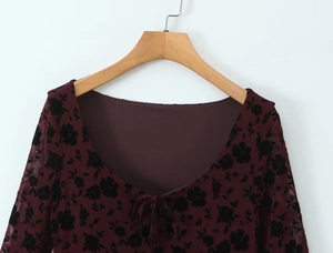 Detail of burgundy floral mesh top with low U-neckline and delicate front tie strings