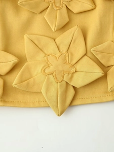 Gros plan du tissu sergé jaune montrant les détails de la décoration florale 3D