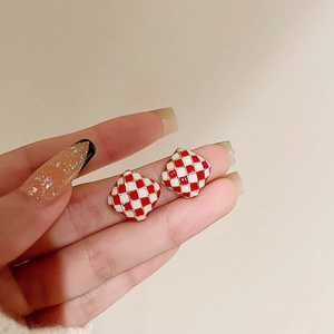 Detail of square red and white checkerboard earrings with elegant gold trim edges
