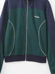 Détail de la veste de sport bicolore avec fermeture éclair, liseré blanc et écusson