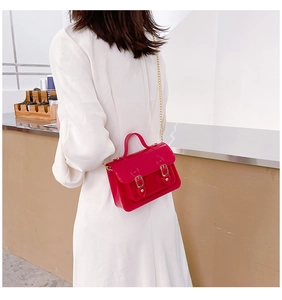 Back view of a woman wearing a red jelly Cambridge crossbody bag with gold chain strap.