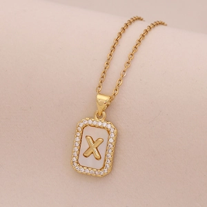 Détail du pendentif en or 18K avec incrustation de nacre et gravure de la lettre X