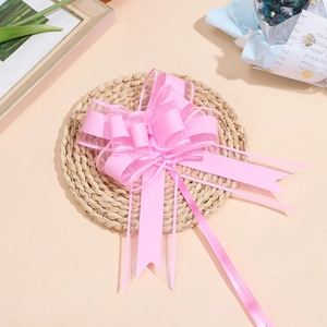 Vista dettagliata di un fiocco regalo in organza e raso rosa su un tappetino intrecciato