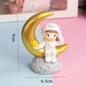 Detailed size view of an astronaut figurine on a golden moon, 8cm height by 6.5cm width