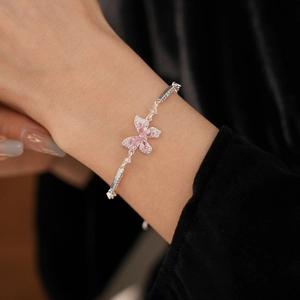 Détail d'un bracelet papillon en argent avec zircon rose porté au poignet féminin
