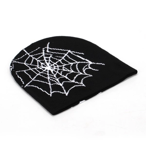 Détail du bonnet en maille noire avec motif toile d'araignée blanche et texture douce
