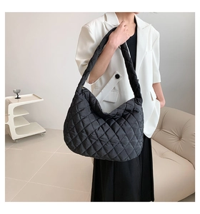 Detailed view of black quilted tote bag with diamond pattern on a shoulder strap model