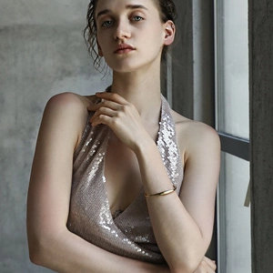 Minimalist 18K gold plated stainless steel twisted bangle worn by a model in lifestyle shot