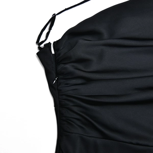 Détail d'une robe en satin noir avec un design froncé latéral et une fermeture éclair invisible