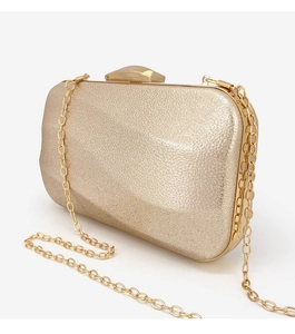 Detailed macro of a gold champagne evening clutch with shiny textured finish and chain strap