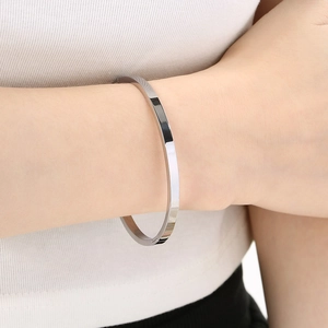 Minimalist polished stainless steel bangle in bright silver finish worn by a model