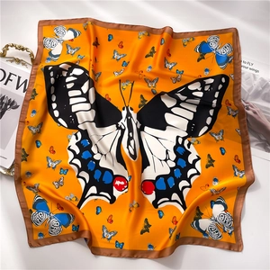 Gros plan détaillé du foulard en soie orange avec motif papillon et bordure marron