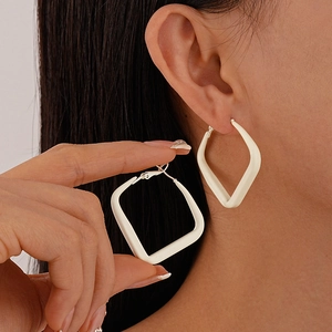 Close-up of cream-white geometric earrings with matte finish worn by a model