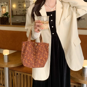 Close-up of brown floral corduroy tote bag in a cozy cafe setting for women