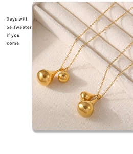Close-up of golden teardrop pendant earrings with delicate chains on a beige jewelry tray