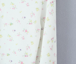 Gros plan sur un tissu en maille côtelée blanche avec des motifs floraux roses et jaunes