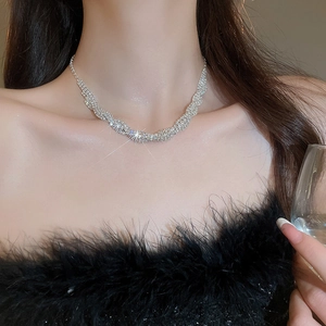 Close-up of sparkling rhinestone pavé twist necklace on model in black feather dress