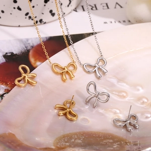 Close-up of gold and silver bow-knot necklaces and earrings on a pearl shell tray