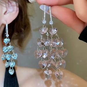 Detail view of heart-shaped crystal tassel earrings in pink and blue variations