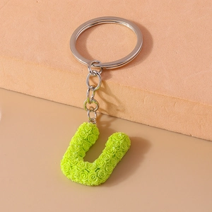 Detail of neon green letter U keychain with intricate miniature rose flower texture