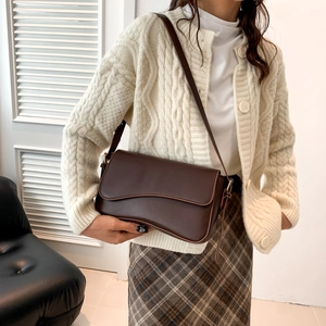 Chic dark brown crossbody bag with unique wave flap design in a lifestyle setting