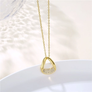 Detail of 18K gold Mobius necklace featuring irregular geometric pendant and zircon inlay