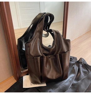 Detail view of large dark brown retro tote bag with front pocket and pleated design