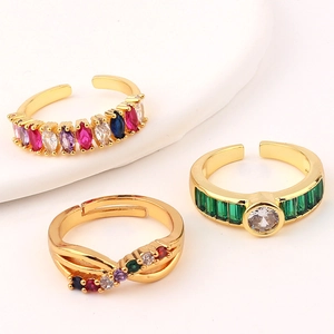 Close-up of gold-plated adjustable rings featuring emerald green and colorful zircons