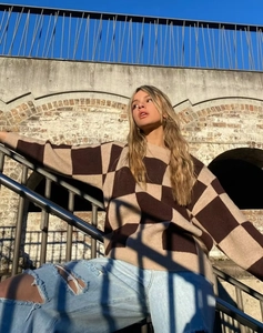 Close-up of brown and beige checkerboard knit sweater with loose fit and crew neck design
