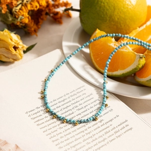 Classic 18K gold stainless steel necklace with blue turquoise beads on a vintage book